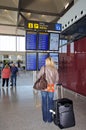 Woman reading flight information in terminal three at Malaga airport, Spain.