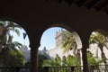 Spanish architecture. View through the arches of the palace. on palms garden in a sunny day Royalty Free Stock Photo