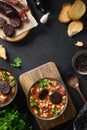 Spanish asturiana fabada with chorizo and morcilla on black background.