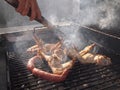 A hand turning chicken wings and white sausages over, Spanish barbeque Royalty Free Stock Photo