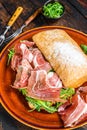 Spanish bocadillo de jamon, serrano ham sandwich on ciabatta bread with arugula. Dark wooden background. Top view Royalty Free Stock Photo