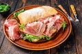 Spanish bocadillo de jamon, serrano ham sandwich on ciabatta bread with arugula. Dark wooden background. Top view Royalty Free Stock Photo