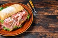 Spanish bocadillo de jamon, serrano ham sandwich on ciabatta bread with arugula. Dark wooden background. Top view. Copy space Royalty Free Stock Photo