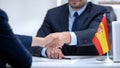 Spanish boss signing employment contract with immigrant employee, shaking hand Royalty Free Stock Photo