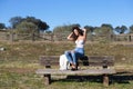 Spanish, brunette, curly-haired woman sits on a bench on the path leading to the forest. She is dressed in jeans and a white top Royalty Free Stock Photo