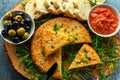Spanish classic tortilla with potatoes, olives, tomatoes, rucola, bread and herbs.