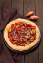 Spanish coca with onion and anchovy on a dark wooden background. Traditional vegetarian pizza or tarte in Spain