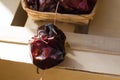 Spanish dried nyora pepper on thread in wicker basket, on wood box, bright red color, sunlight fleck