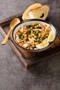 Spanish Easter dish called potaje de vigilia using cod with chickpeas, smoked paprika and spinach close-up in a bowl on the wooden