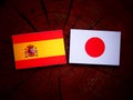 Spanish flag with Japanese flag on a tree stump isolated