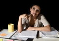 Spanish girl studying tired and bored at home late night absent minded looking thoughtful and happy Royalty Free Stock Photo