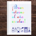 In Spanish Good return to the school year written on a sheet of school notebook with scissors, calculator, compass, eraser