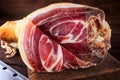 Spanish ham, bellota, jamon serrano, crudo, italian prosciutto, whole leg, parma ham cut with a knife and lying on a wooden board