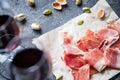 Spanish ham jamon serrano or Italian prosciutto crudo, glasses of red wine and pistachios Royalty Free Stock Photo