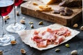 Spanish ham jamon serrano or Italian prosciutto crudo with sliced Italian hard cheese, homemade dried meat salami, red wine Royalty Free Stock Photo