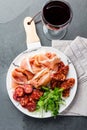 Spanish ham serrano and salami on white marbled plate an red wine. Top view. Royalty Free Stock Photo