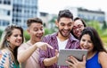 Spanish hipster student with tablet computer and group of cheering international students