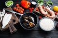 Spanish paella ingredients with rice, prawns, cuttlefish and mussel on black wooden table Royalty Free Stock Photo