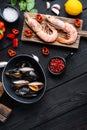 Spanish paella ingredients with rice, prawns, cuttlefish and mussel on black wooden table, top view Royalty Free Stock Photo