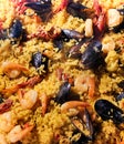 Spanish paella with large prawns and other seafood cooked in a wok pan on the street.