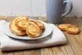 Spanish palmiers on a plate with a cup on wooden surface