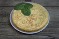 Spanish potato omelette called Tortilla de patatas with fresh leaves on a white plate on wooden rustic background.Delicious Royalty Free Stock Photo