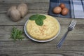 Spanish potato omelette called Tortilla de patatas on a plate, with fresh leaves , eggs and potatoes on wooden rustic background. Royalty Free Stock Photo