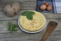 Spanish potato omelette called Tortilla de patatas on a plate, with fresh leaves , eggs and potatoes on wooden rustic background. Royalty Free Stock Photo