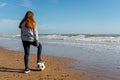 Spanish pre-adolescent girl looking at the horizon on the shore of Burriana beach stepping on her soccer ball with one