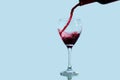 Spanish red wine flows lively from a bottle into a glass against a blue background. Royalty Free Stock Photo