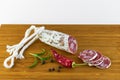 Spanish salami also sliced with dried red chili pepper and black pepper and rosemary on a wooden board Royalty Free Stock Photo