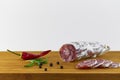 Spanish salami also sliced with dried red chili pepper and black pepper and rosemary on a wooden board Royalty Free Stock Photo