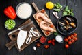 Spanish seafood paella ingredients, rice,prawns, mussels, peas on black wooden background, flat lay