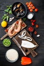 Spanish seafood paella ingredients, rice,prawns, mussels, peas on  black wooden background, flat lay Royalty Free Stock Photo