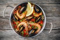 Spanish seafood paella with mussels, shrimps and chorizo sausages in traditional pan on wooden background. Royalty Free Stock Photo