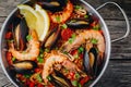 Spanish seafood paella with mussels, shrimps and chorizo sausages in traditional pan on wooden background. Royalty Free Stock Photo