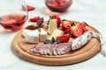 Spanish tapas sliced sausages fuet and Camembert cheese, strawberries and glass rose wine on a wooden cutting board Royalty Free Stock Photo