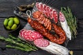 Spanish tapas sliced sausages salami, fuet and chorizo on a wooden cutting board. Black wooden background. Top view Royalty Free Stock Photo