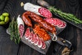 Spanish tapas sliced sausages salami, fuet and chorizo on a wooden cutting board. Black wooden background. Top view Royalty Free Stock Photo