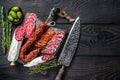 Spanish tapas sliced sausages salami, fuet and chorizo on a wooden cutting board. Black wooden background. Top view Royalty Free Stock Photo