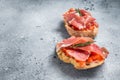 Spanish Tapas with tomatoes and cured Slices of jamon iberico ham, fresh toasts. Gray background. Top view. Copy space