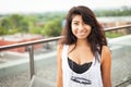 Spanish woman smiling at the camera. She is outside on the top of the building