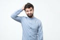 Spanish young man with black beard thinking, scratching his head. Royalty Free Stock Photo