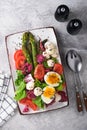 Sparagus, tomato, lettuce, mozzarella, black sesame, flax, oil olive salad and soft boiled egg on rectangular ceramic plate on Royalty Free Stock Photo