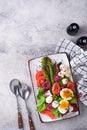 Sparagus, tomato, lettuce, mozzarella, black sesame, flax, oil olive salad and soft boiled egg on rectangular ceramic plate on Royalty Free Stock Photo
