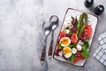 Sparagus, tomato, lettuce, mozzarella, black sesame, flax, oil olive salad and soft boiled egg on rectangular ceramic plate on Royalty Free Stock Photo