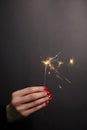 Sparkler in woman hand with red nail polish Royalty Free Stock Photo