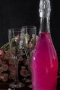 Sparkling brilliant raspberry drink. Champagne in two glasses stands on a wooden table with ice. For flowers and a garland Royalty Free Stock Photo
