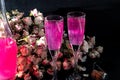 Sparkling brilliant raspberry drink. Champagne in two glasses stands on a wooden table with ice. For flowers and a garland Royalty Free Stock Photo