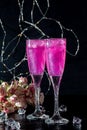 Sparkling brilliant raspberry drink. Champagne in two glasses stands on a wooden table with ice. For flowers and a garland Royalty Free Stock Photo